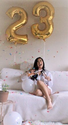 a woman sitting on a couch with balloons and confetti in front of her