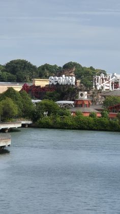 there is a bridge that goes over the water to an amusement park in the background