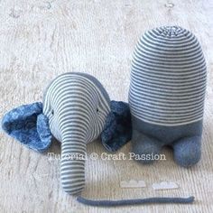 an elephant made out of yarn sitting on the floor next to a piece of fabric