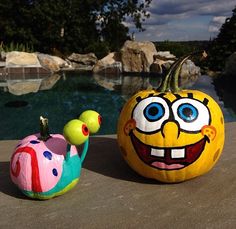 two pumpkins sitting next to each other with faces painted on them, near a pool