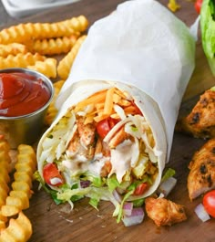 chicken wrap with lettuce, tomatoes and french fries next to ketchup