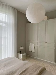 a bedroom with white furniture and curtains on the window sill, along with a large bed