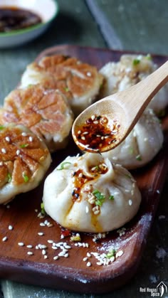 some dumplings are sitting on a cutting board with a wooden spoon