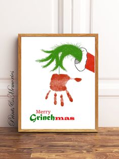 a christmas card with the grin handprinted on it, next to a wooden frame