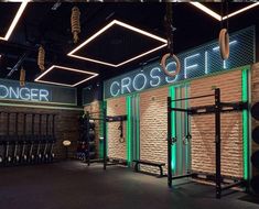 a gym with rows of crossfit equipment and neon signs on the wall above them