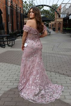 a woman in a pink dress is standing on the sidewalk and looking off into the distance