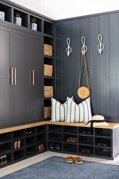 a bench with pillows and shoes on it in a room that has blue walls, shelving units, and wooden flooring