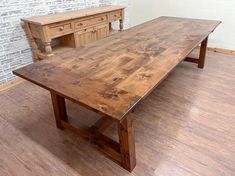 a wooden table sitting on top of a hard wood floor next to a brick wall