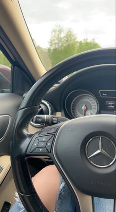 a person is sitting in the driver's seat of a car with their feet on the steering wheel