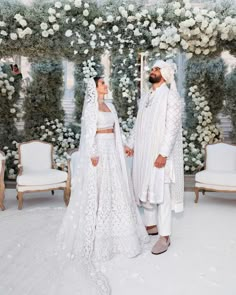 the newly married couple are standing in front of an archway with white flowers and greenery