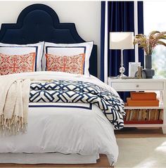 a bed with blue headboard and white comforter next to a window in a bedroom