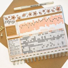 an open planner with some stickers on top of it and a pen next to it