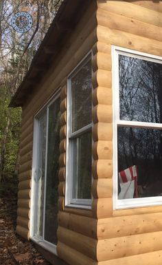 a small log cabin with two windows and an american flag on the window sill