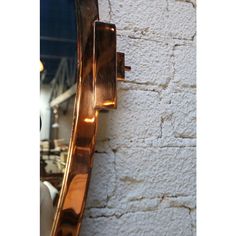 a large mirror mounted to the side of a wall next to a white brick wall