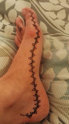 a woman's foot with black dots on it and a tattoo design on the side