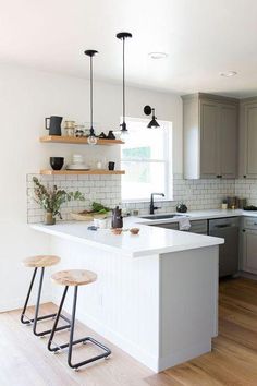 a kitchen with two stools in front of the island and shelves on the wall