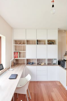 an office with white cabinets and wood flooring in the center, along with a laptop computer on a desk