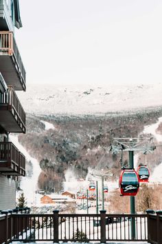 a ski lift going up the side of a snow covered mountain next to a building