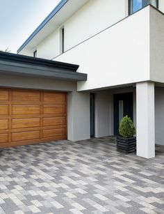 a large white house with two garages and a potted plant in the driveway