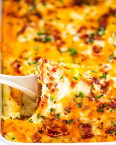 a casserole dish with cheese, bacon and parsley on top is being scooped from the casserole