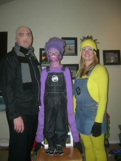 three people dressed up in costumes standing next to each other on a wooden table and posing for the camera