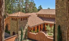 an aerial view of a house with trees in the background and bushes on the ground