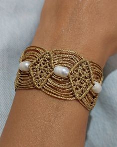 a close up of a person's arm wearing a bracelet with pearls on it