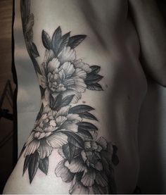 a woman's stomach with black and white flowers on the side, in front of her