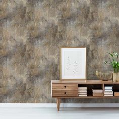 a table with a plant and some books on it in front of a wallpapered background