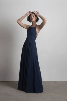 a woman in a long blue dress is holding her head with one hand and looking off to the side