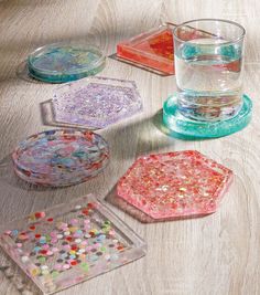 four glass coasters with different designs on them sitting on a wooden table next to a cup