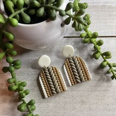 the earrings are made out of woven material and have white buttons on each earring