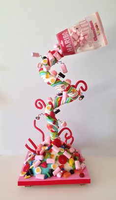 a candy bar sculpture on top of a pink base with sprinkles and candies