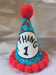 a dr seuss thing 1 birthday hat with pom - poms on it