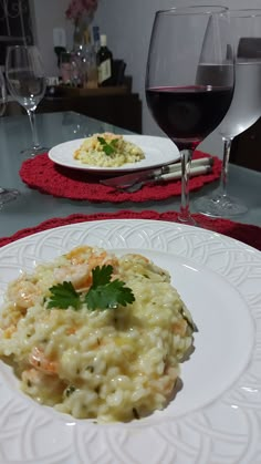 a white plate topped with macaroni and cheese next to a glass of wine