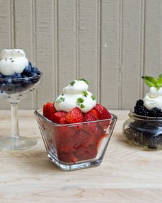 three desserts in small glass dishes on a wooden table with white and blackberries