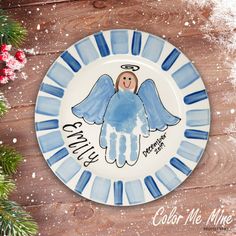 a blue and white plate with an angel painted on it, surrounded by pine branches