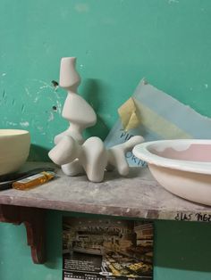 a table topped with bowls and vases next to a wall covered in peeling paint