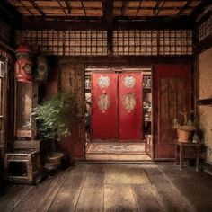 a red door is in the middle of a room with two chairs and a potted plant