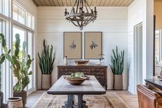 a dining room with potted plants in the corner and a chandelier hanging from the ceiling