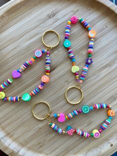 several different colored beads are on a wooden tray with gold rings and keychains