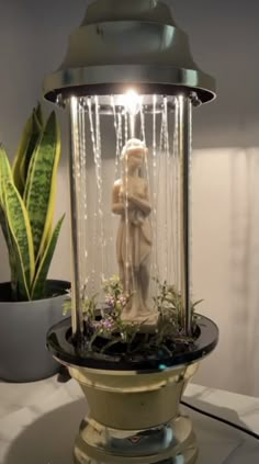 a statue in a glass jar with water running down it's sides and plants growing inside