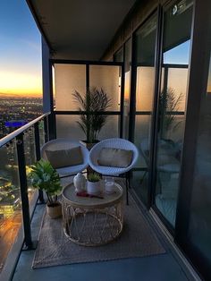 two chairs sitting on top of a balcony next to a table and potted plant