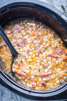 a close up of a bowl of soup with meat and beans in it on a table