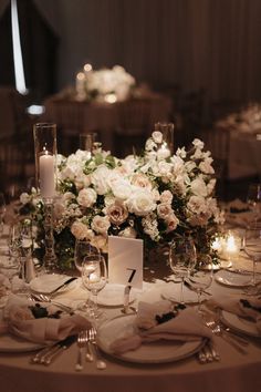 the table is set with white flowers and candles for an elegant wedding reception or special event