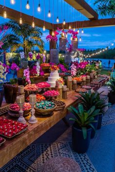 a table filled with lots of desserts and flowers on top of wooden tables next to water