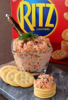 crackers and dip in a glass bowl on a table next to a box of ritz crackers