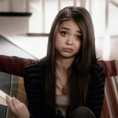 a young woman sitting on top of a couch holding a piece of paper in her hand