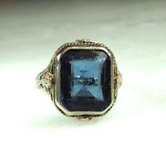 This is an antique 14K white gold filigree ring with yellow gold & rose gold accents around the bezel.  The stone is a sapphire blue glass.  It does have considerable wear on its facets.  This can be polished out by your local jeweler.  The ring face measures 15mm x12mm.  The band is sized at a 6.  Total weight of the ring is 3.4 grams.  The band is stamped 14K inside.  Light antique wear can be expected. Filigree Ring Gold, The Ring Face, Rose Gold Accents, Ladies Ring, Gold Filigree, Filigree Ring, Antique Art Deco, Sapphire Blue, Antique Art