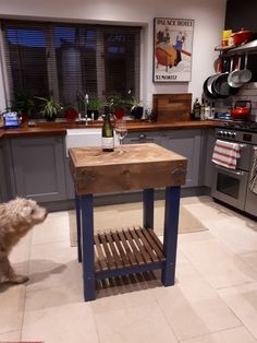 a dog standing next to a kitchen island with a wine bottle on it's side